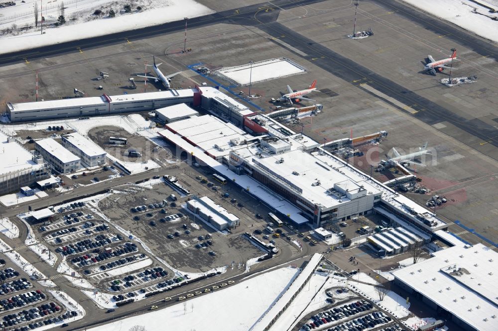 Schönefeld from the bird's eye view: Winter covered with snow runways, taxiways, terminal building and old DDR terminal from INTERFLUG times at Berlin - Schonefeld