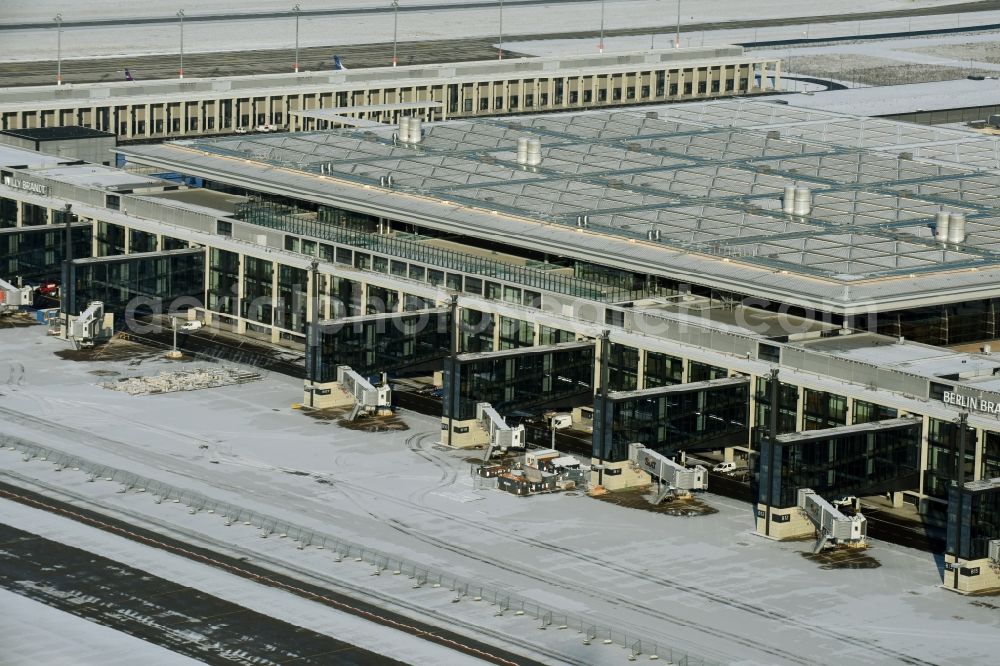 Schönefeld from the bird's eye view: Wintry snowy dispatch building and terminals on the premises of the airport BER in Schoenefeld in the state Brandenburg