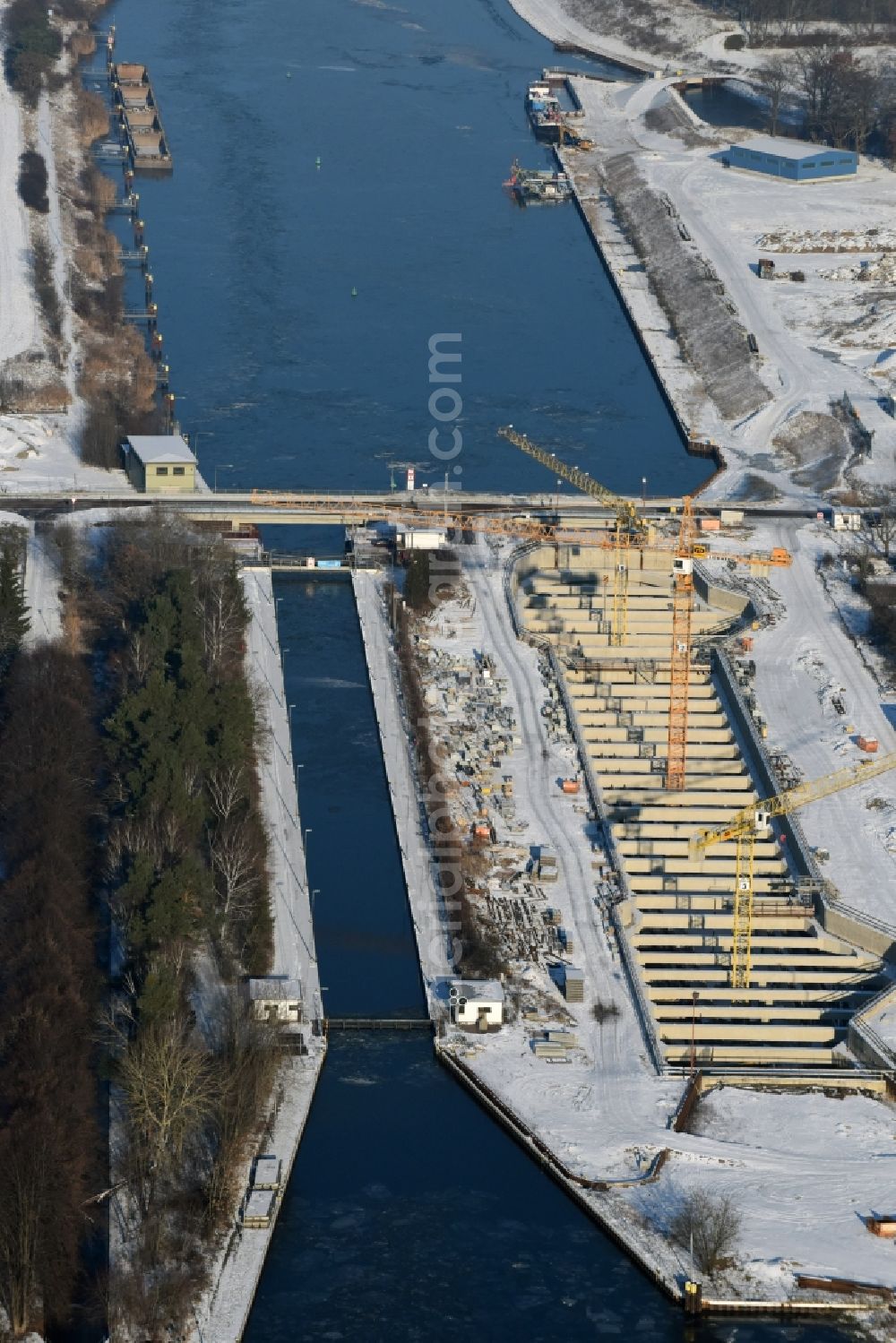 Zerben from the bird's eye view: Wintry snowy construction site at the Zerben sluice, bridge and the riverside of the Elbe-Havel-Canel in the state Saxony-Anhalt