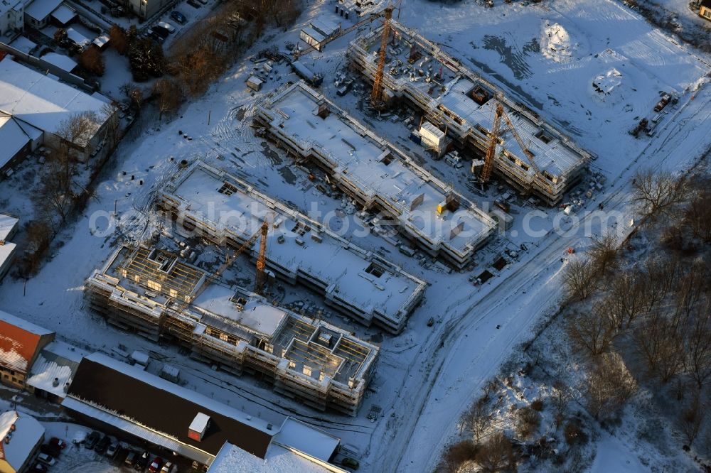 Berlin from above - Wintry snowy construction site to build a new multi-family residential complex An der Schule destrict Mahlsdorf in Berlin