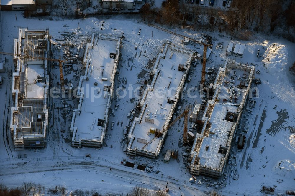 Berlin from above - Wintry snowy construction site to build a new multi-family residential complex An der Schule destrict Mahlsdorf in Berlin