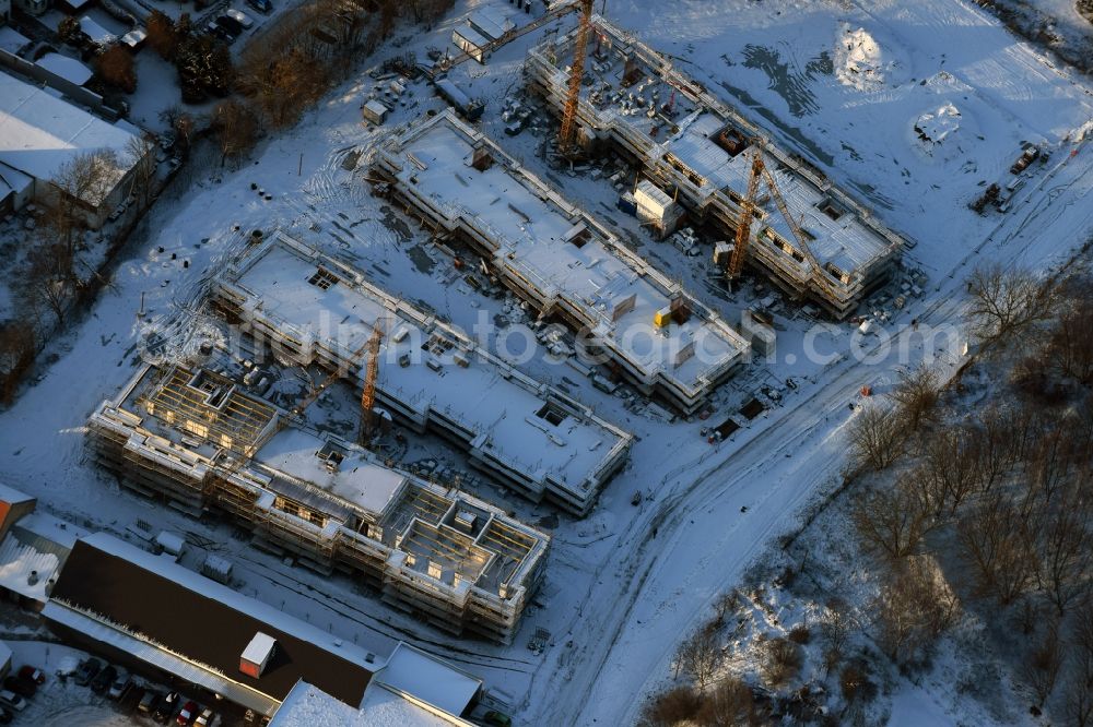 Berlin from above - Wintry snowy construction site to build a new multi-family residential complex An der Schule destrict Mahlsdorf in Berlin