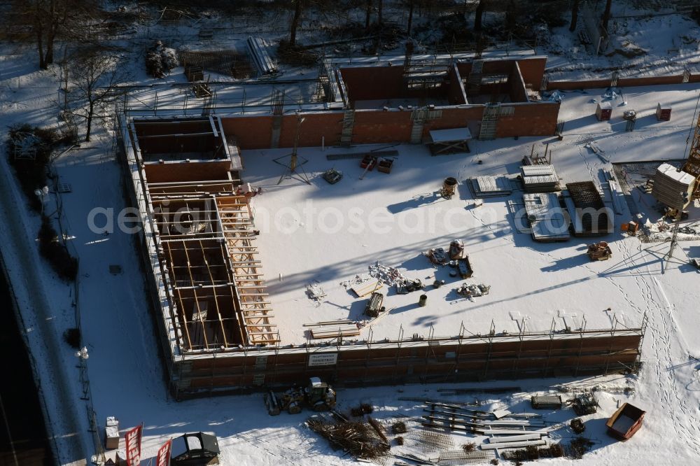 Hohen Neuendorf from the bird's eye view: Wintry snowy construction works of the shopping center at the former OBI - Hardware at Schoenfliesser street in Hohen Neuendorf in Brandenburg. GVG Project Development Company plans to revitalize the brain area by demolition of disused construction market and the new Spacious a modern local supply and service center