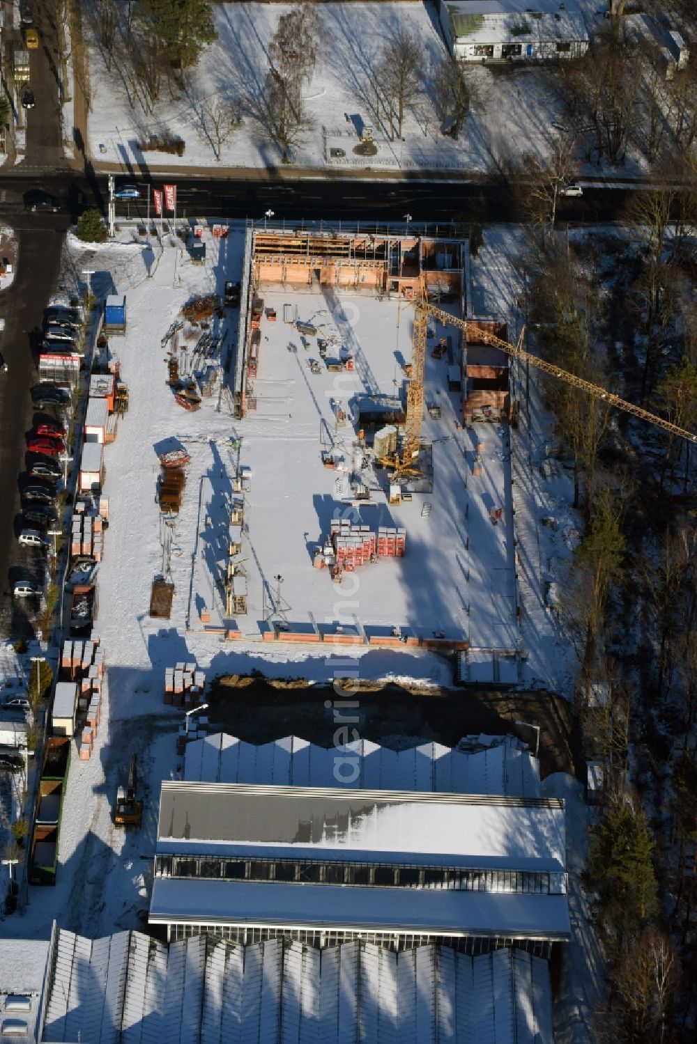 Hohen Neuendorf from the bird's eye view: Wintry snowy construction works of the shopping center at the former OBI - Hardware at Schoenfliesser street in Hohen Neuendorf in Brandenburg. GVG Project Development Company plans to revitalize the brain area by demolition of disused construction market and the new Spacious a modern local supply and service center