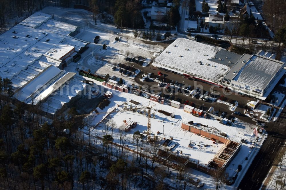 Aerial photograph Hohen Neuendorf - Wintry snowy construction works of the shopping center at the former OBI - Hardware at Schoenfliesser street in Hohen Neuendorf in Brandenburg. GVG Project Development Company plans to revitalize the brain area by demolition of disused construction market and the new Spacious a modern local supply and service center