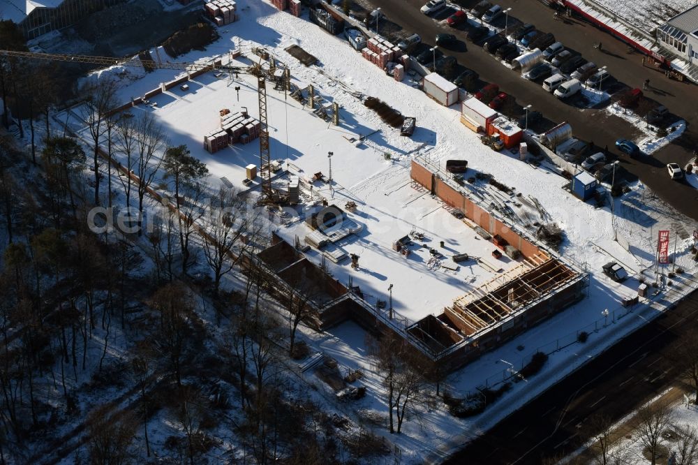 Hohen Neuendorf from above - Wintry snowy construction works of the shopping center at the former OBI - Hardware at Schoenfliesser street in Hohen Neuendorf in Brandenburg. GVG Project Development Company plans to revitalize the brain area by demolition of disused construction market and the new Spacious a modern local supply and service center