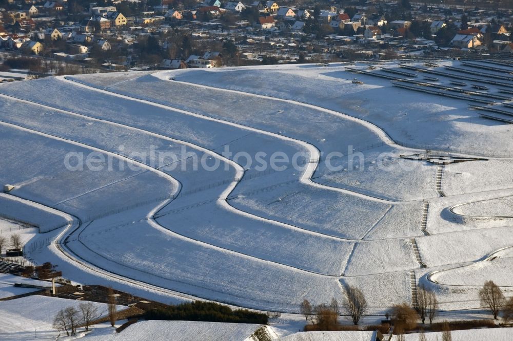 Aerial photograph Magdeburg - Wintry snowy piled landfill mountain of Solar Park Magdeburg in Saxony-Anhalt. Under the direction of the WSB Group of Companies of Magdeburg solar park was built on the former landfill site Cracauer Anger