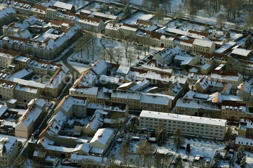 Altlandsberg from the bird's eye view: Wintry snowy townscape with streets and houses of the residential areas in Altlandsberg in the state Brandenburg