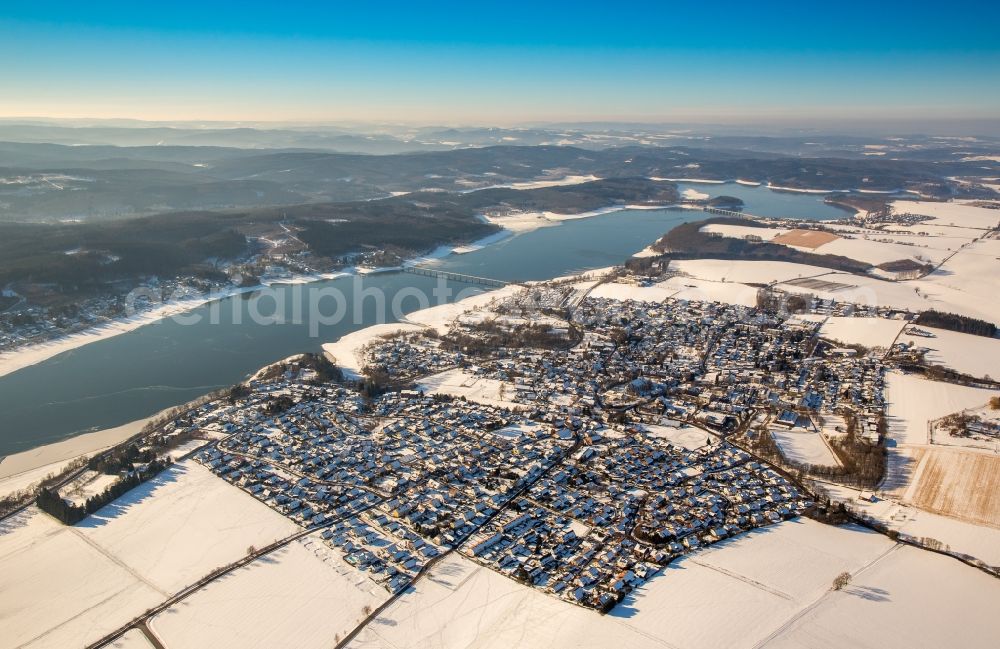 Aerial photograph Möhnesee - Wintry snowy townscape with streets and houses of the residential areas in the district Koerbecke at the Moehne lake in Moehnesee in the state North Rhine-Westphalia