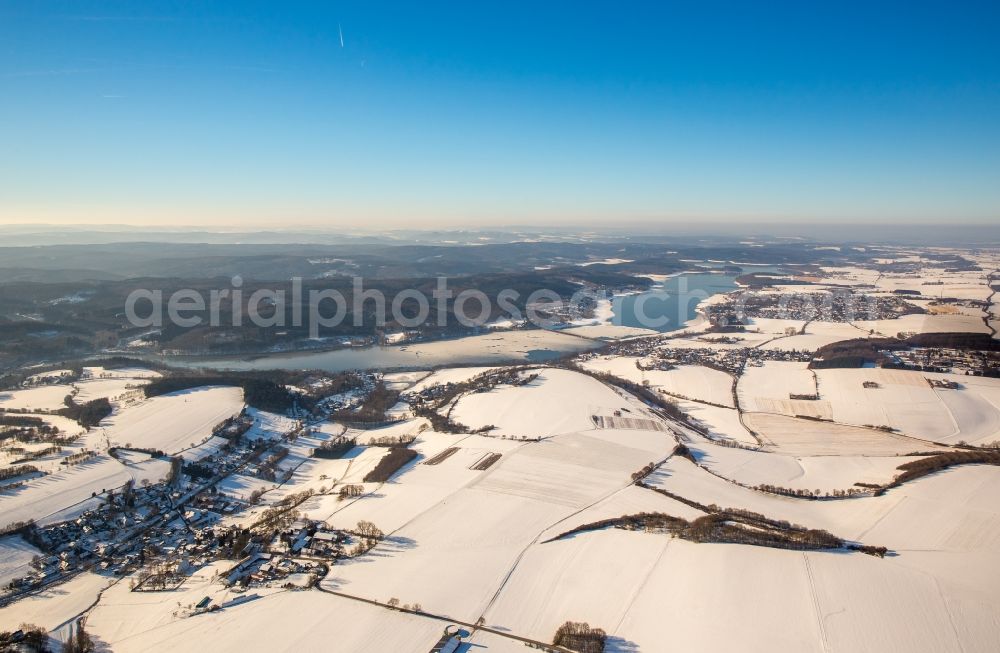 Möhnesee from the bird's eye view: Wintry snowy townscape with streets and houses of the residential areas in the district Wamel near the river Moehn in Moehnesee in the state North Rhine-Westphalia