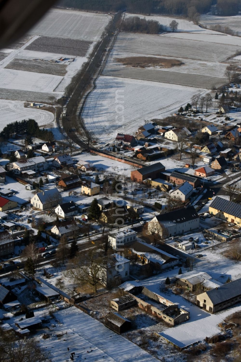 Mühlenbecker Land from the bird's eye view: Wintry snowy townscape of Schoenfliess Bergfelder Chaussee corner Dorfstrasse with houses of the residential areas in Muehlenbecker Land in the state Brandenburg