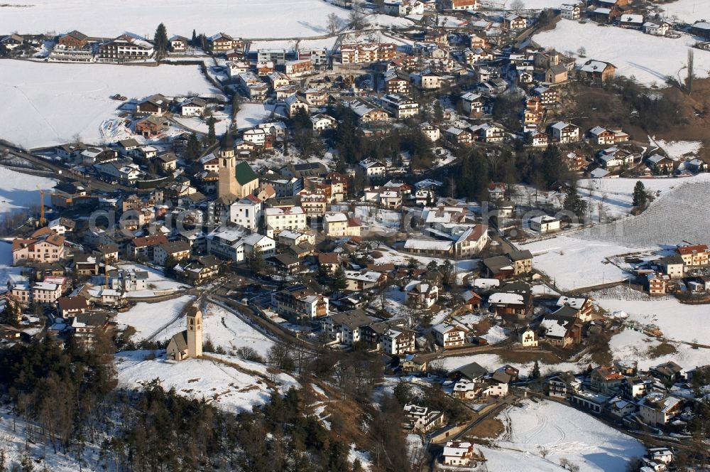 Völs am Schlern - Fié allo Sciliar from the bird's eye view: Wintry snowy townscape with streets and houses of the residential areas in Voels am Schlern - Fie allo Sciliar in Trentino-Alto Adige, Italy