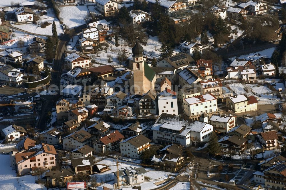 Völs am Schlern - Fié allo Sciliar from the bird's eye view: Wintry snowy townscape with streets and houses of the residential areas in Voels am Schlern - Fie allo Sciliar in Trentino-Alto Adige, Italy