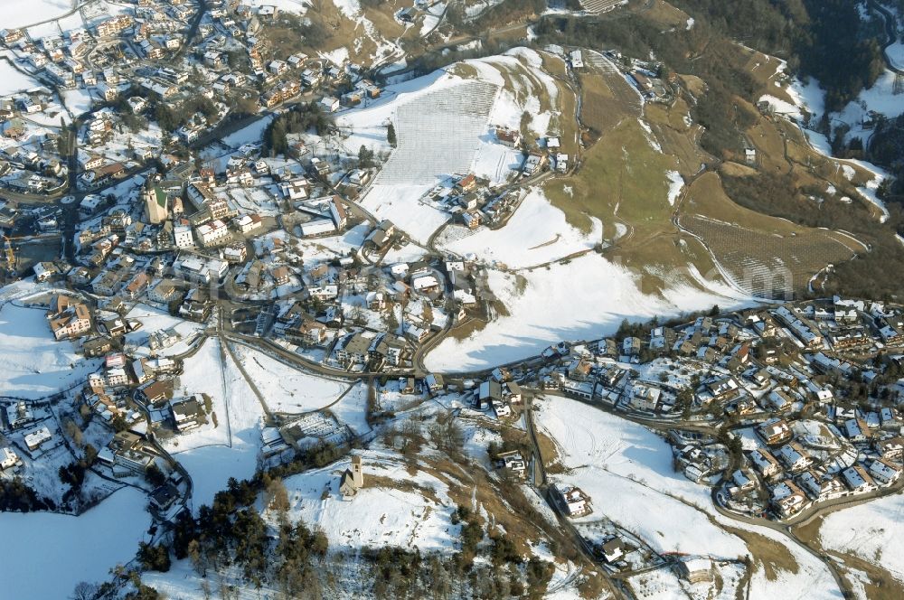 Völs am Schlern - Fié allo Sciliar from the bird's eye view: Wintry snowy townscape with streets and houses of the residential areas in Voels am Schlern - Fie allo Sciliar in Trentino-Alto Adige, Italy