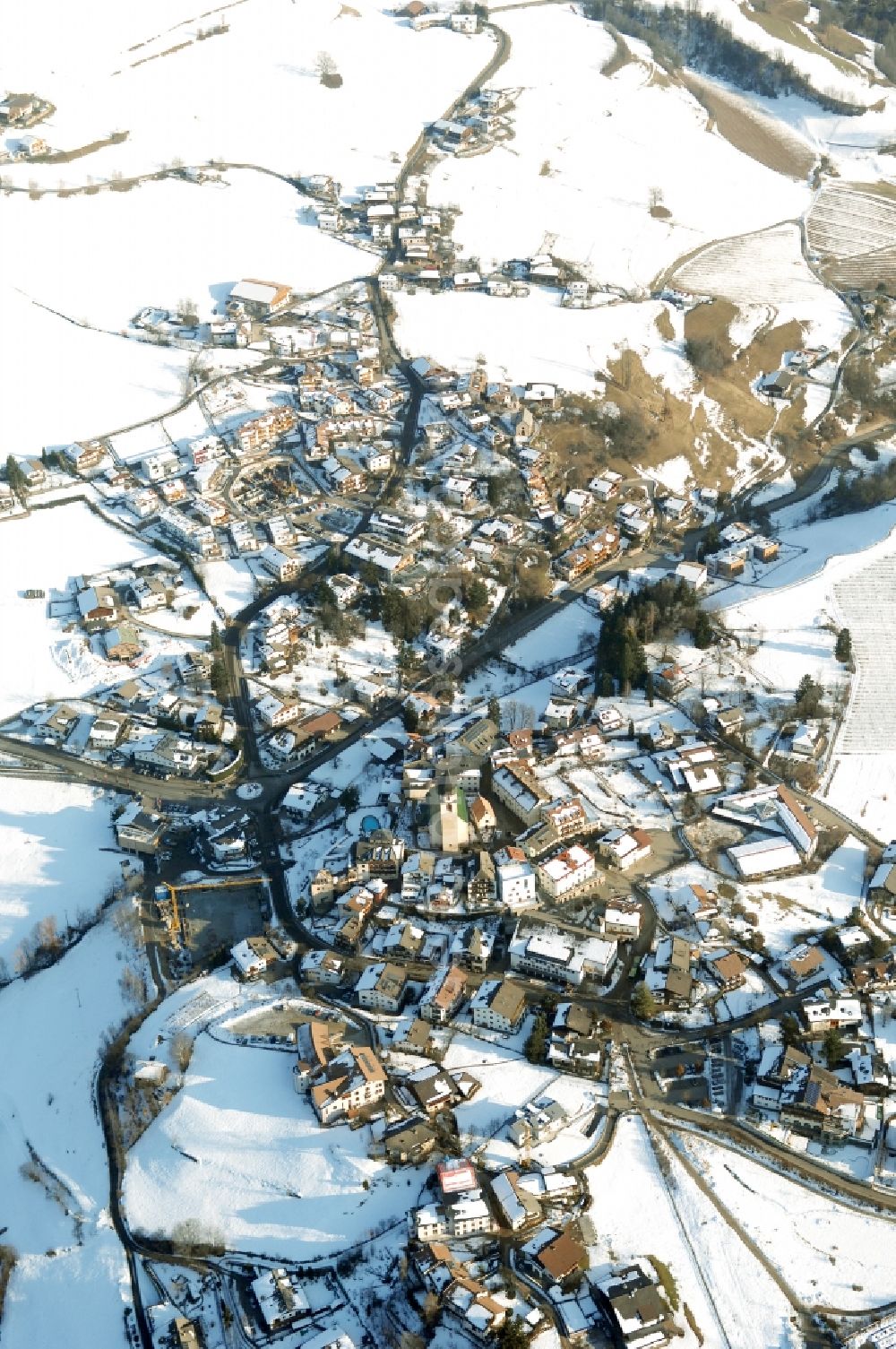 Völs am Schlern - Fié allo Sciliar from the bird's eye view: Wintry snowy townscape with streets and houses of the residential areas in Voels am Schlern - Fie allo Sciliar in Trentino-Alto Adige, Italy