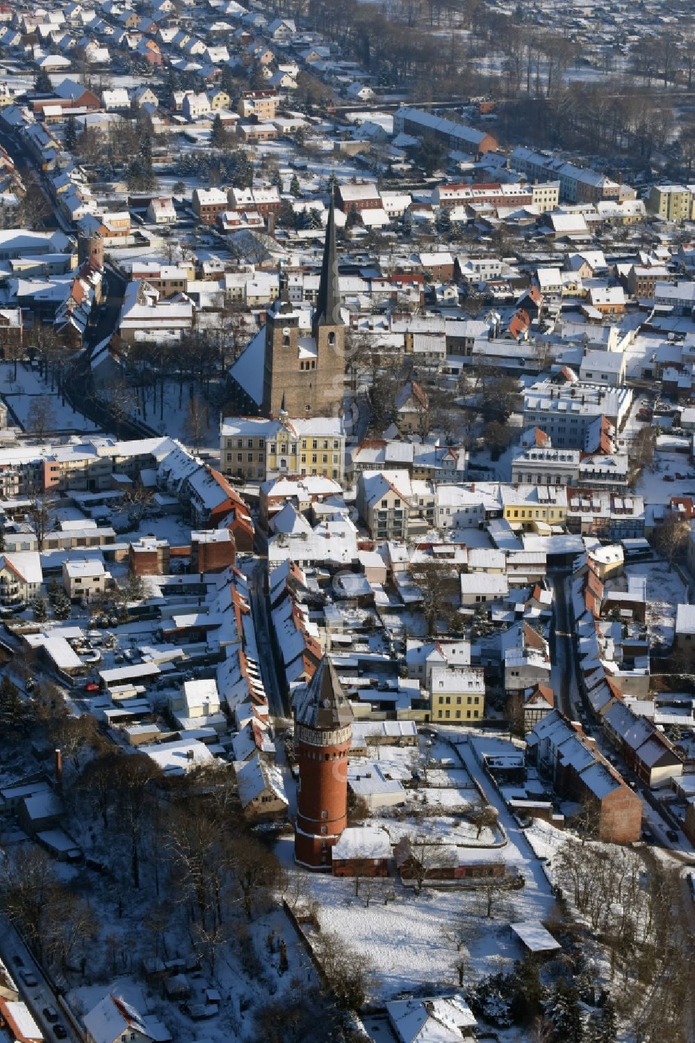 Burg from above - Wintry snowy townscape with streets and houses of the residential areas in Burg as well as the course of the river Ihle, the Church building Unser Lieben Frauen and the water tower in the state Saxony-Anhalt