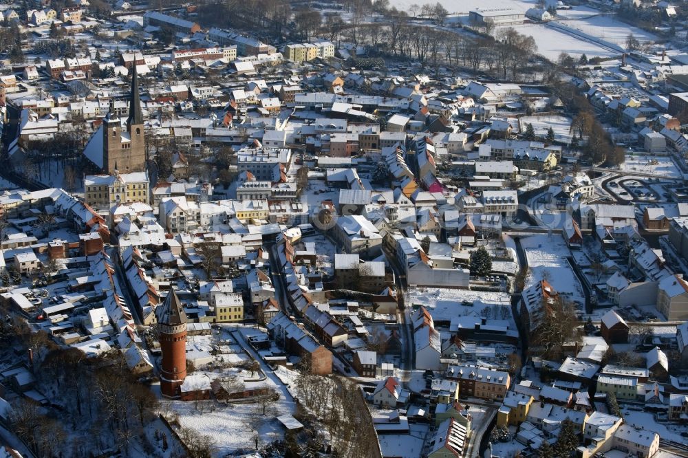 Burg from the bird's eye view: Wintry snowy townscape with streets and houses of the residential areas in Burg as well as the course of the river Ihle, the Church building Unser Lieben Frauen and the water tower in the state Saxony-Anhalt