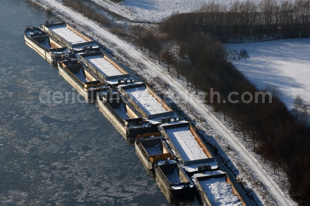 Burg from the bird's eye view: Wintry snowy channel course with moored barge inland thrust units on the banks of the Elbe-Havel Canal in Burg in Saxony-Anhalt