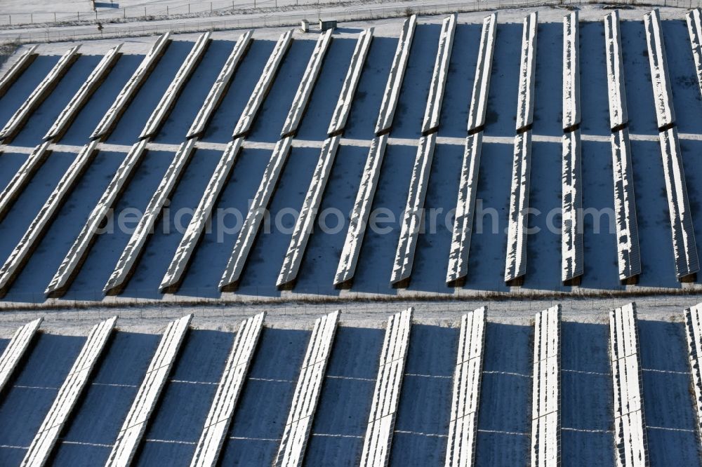 Werneuchen from above - Wintry snowy panel rows of photovoltaic and solar farm or solar power plant on the airfield site in Werneuchen in the state Brandenburg