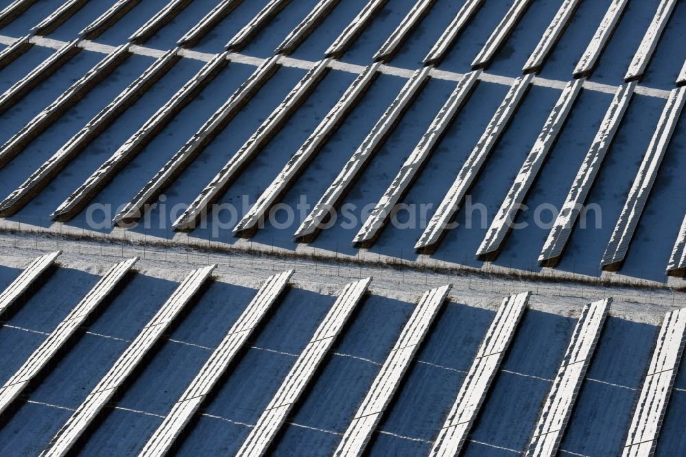 Werneuchen from the bird's eye view: Wintry snowy panel rows of photovoltaic and solar farm or solar power plant on the airfield site in Werneuchen in the state Brandenburg