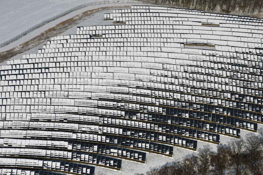 Werneuchen from the bird's eye view: Wintry snowy panel rows of photovoltaic and solar farm or solar power plant in Werneuchen in the state Brandenburg