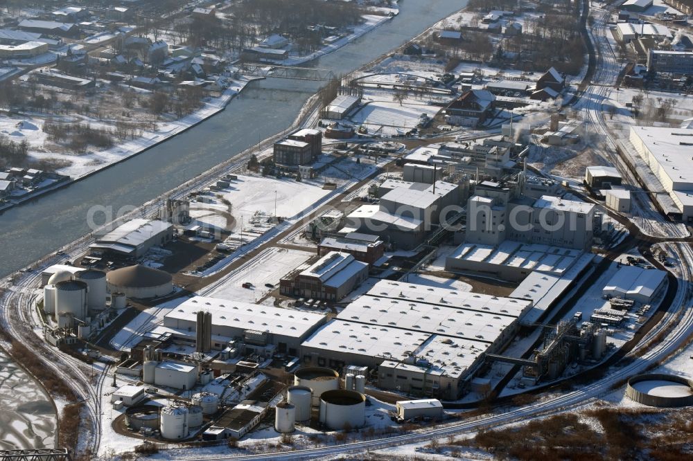 Genthin from the bird's eye view: Wintry snow-covered company grounds and facilities of Waschmittelwerk Genthin GmbH (laundry detergent works) in Genthin in the state of Saxony-Anhalt. The works and facilities area located in the Northern industrial park on the riverbank of the Elbe-Havel-Canal and are part of Hansa Group