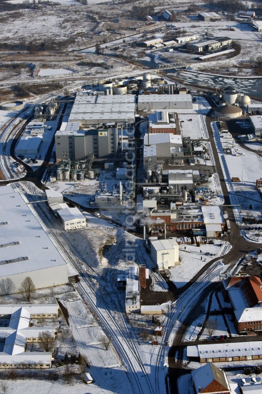 Genthin from the bird's eye view: Wintry snow-covered company grounds and facilities of Waschmittelwerk Genthin GmbH (laundry detergent works) in Genthin in the state of Saxony-Anhalt. The works and facilities area located in the Northern industrial park on the riverbank of the Elbe-Havel-Canal and are part of Hansa Group