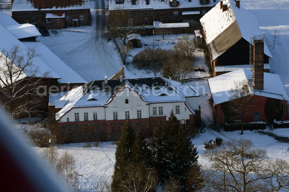 Krüssau from the bird's eye view: Winterly snowy buildings and parks at the mansion of the farmhouse Brandenstein in Kruessau in the state Saxony-Anhalt