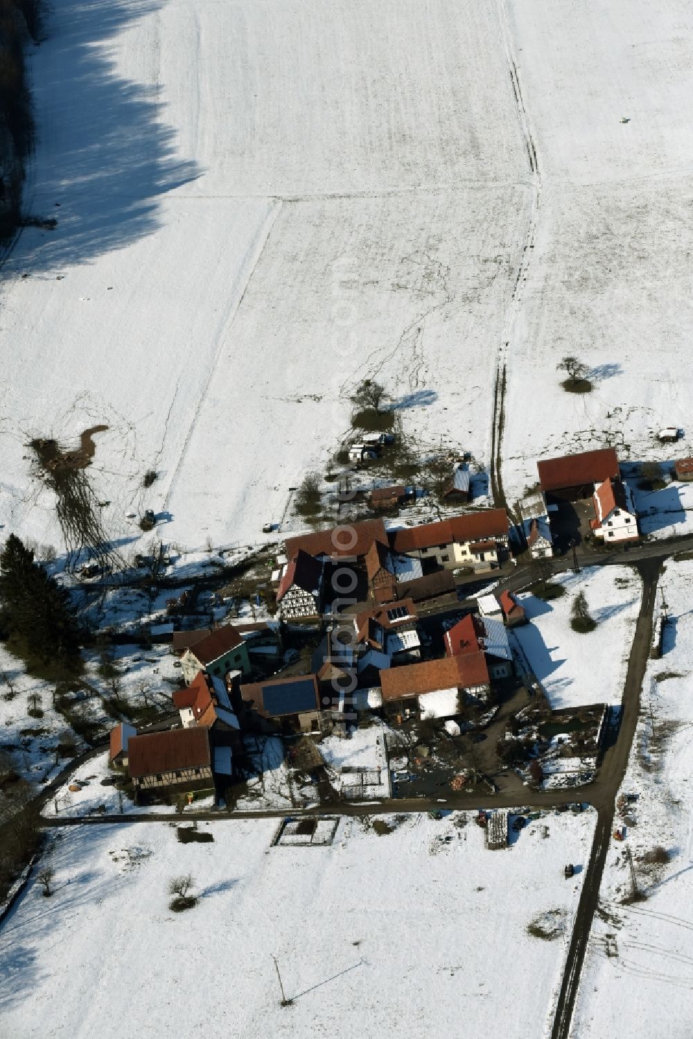 Weilar from the bird's eye view: Wintry snowy Farm on the edge of cultivated fields in Weilar in the state Thuringia