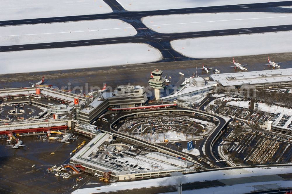 Berlin from the bird's eye view: Wintry snowy Runway with hangar taxiways and terminals on the grounds of the airport in Berlin