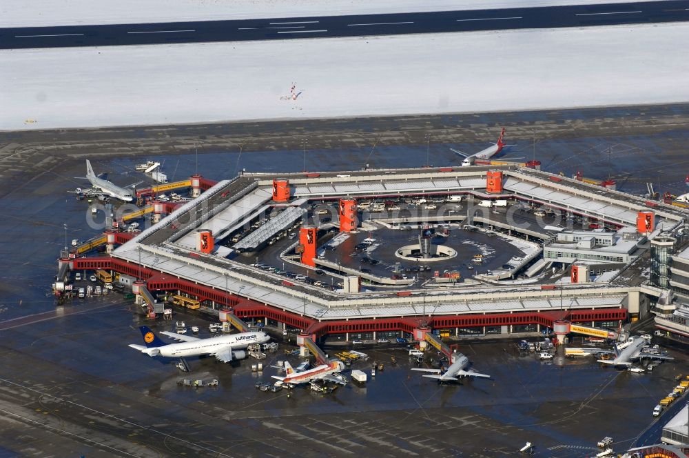 Berlin from the bird's eye view: Wintry snowy Runway with hangar taxiways and terminals on the grounds of the airport in Berlin