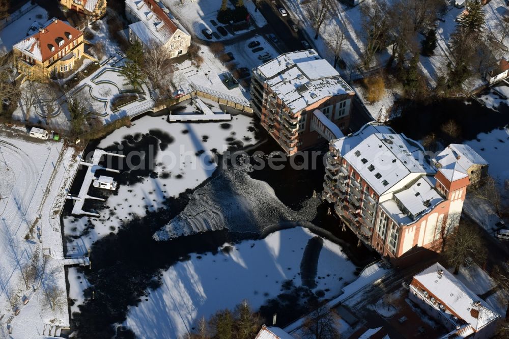 Aerial photograph Brandenburg an der Havel - Winterly snowy historical building Burgmuehle in Brandenburg an der Havel in the state Brandenburg over the course of the river Domstreng with condominiums, assisted living and holiday apartments