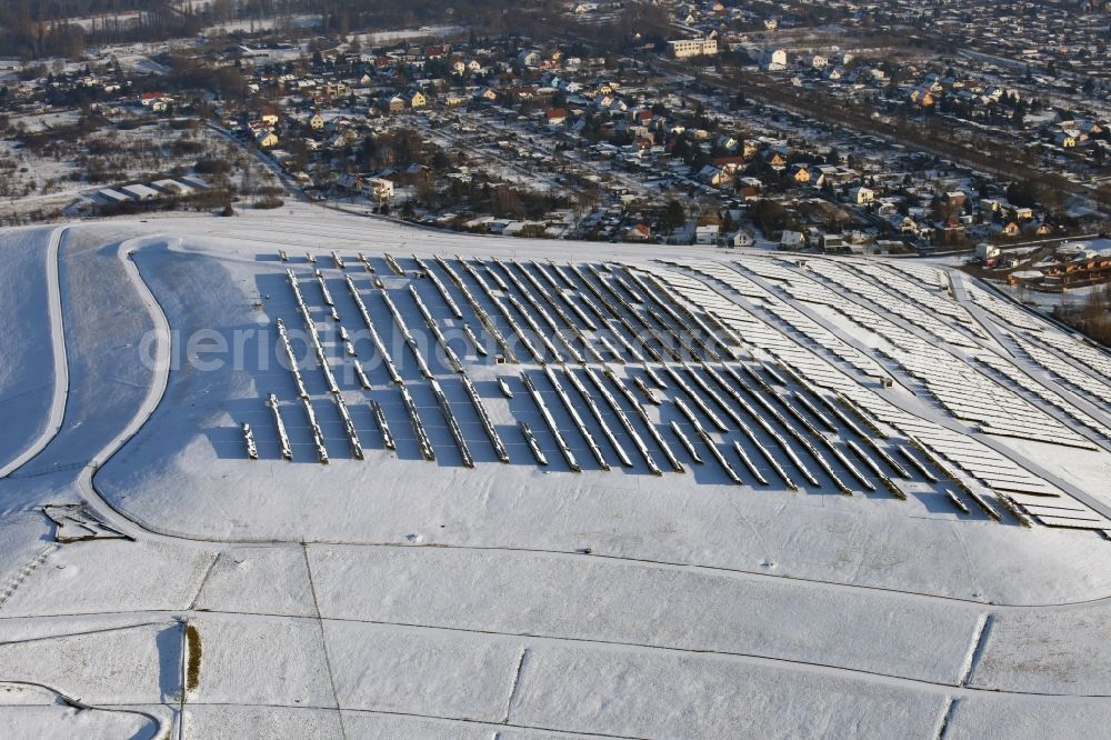 Aerial photograph Magdeburg - Wintry snowy panel rows of photovoltaic and solar farm or solar power plant am Solarpark auf der ehemaligen Hausmuelldeponie Cracauer Anger in Magdeburg in the state Saxony-Anhalt