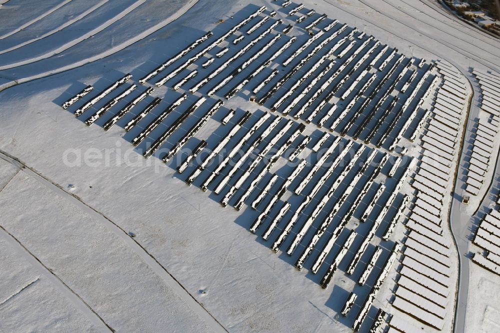 Magdeburg from the bird's eye view: Wintry snowy panel rows of photovoltaic and solar farm or solar power plant am Solarpark auf der ehemaligen Hausmuelldeponie Cracauer Anger in Magdeburg in the state Saxony-Anhalt