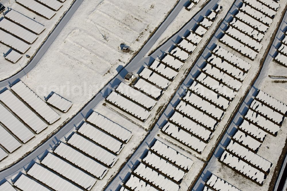 Aerial photograph Magdeburg - Wintry snowy panel rows of photovoltaic and solar farm or solar power plant am Solarpark auf der ehemaligen Hausmuelldeponie Cracauer Anger in Magdeburg in the state Saxony-Anhalt