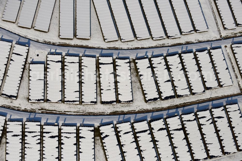 Magdeburg from the bird's eye view: Wintry snowy panel rows of photovoltaic and solar farm or solar power plant am Solarpark auf der ehemaligen Hausmuelldeponie Cracauer Anger in Magdeburg in the state Saxony-Anhalt