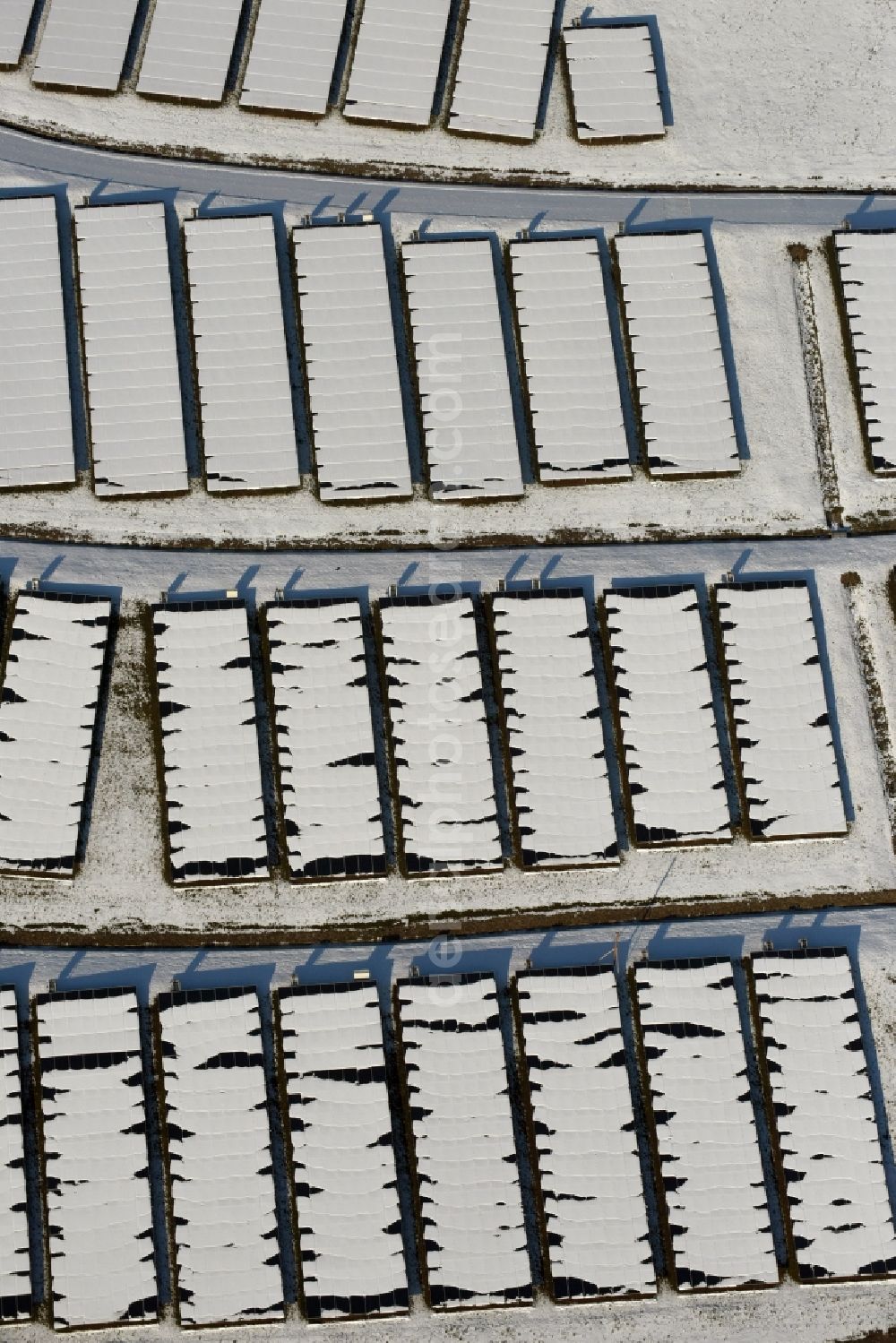 Aerial photograph Magdeburg - Wintry snowy panel rows of photovoltaic and solar farm or solar power plant am Solarpark auf der ehemaligen Hausmuelldeponie Cracauer Anger in Magdeburg in the state Saxony-Anhalt