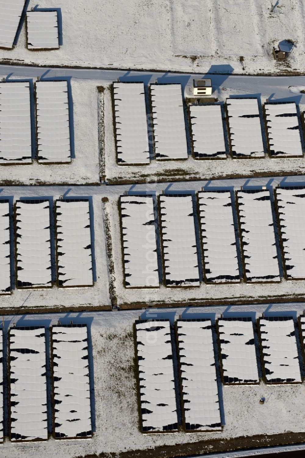 Magdeburg from the bird's eye view: Wintry snowy panel rows of photovoltaic and solar farm or solar power plant am Solarpark auf der ehemaligen Hausmuelldeponie Cracauer Anger in Magdeburg in the state Saxony-Anhalt