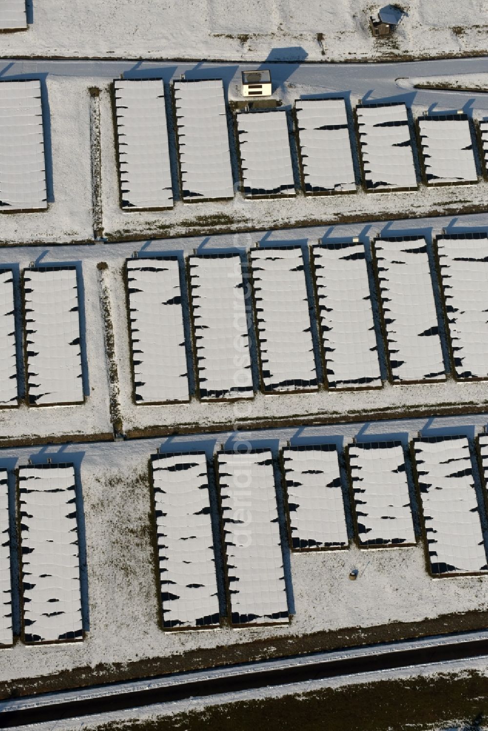 Aerial image Magdeburg - Wintry snowy panel rows of photovoltaic and solar farm or solar power plant am Solarpark auf der ehemaligen Hausmuelldeponie Cracauer Anger in Magdeburg in the state Saxony-Anhalt