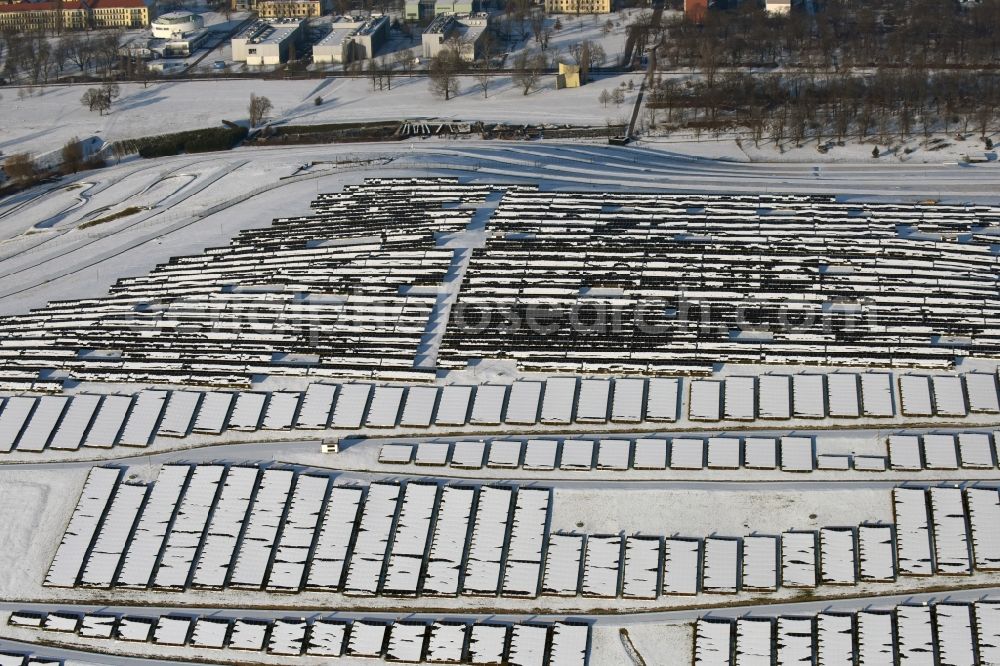 Magdeburg from the bird's eye view: Wintry snowy panel rows of photovoltaic and solar farm or solar power plant am Solarpark auf der ehemaligen Hausmuelldeponie Cracauer Anger in Magdeburg in the state Saxony-Anhalt