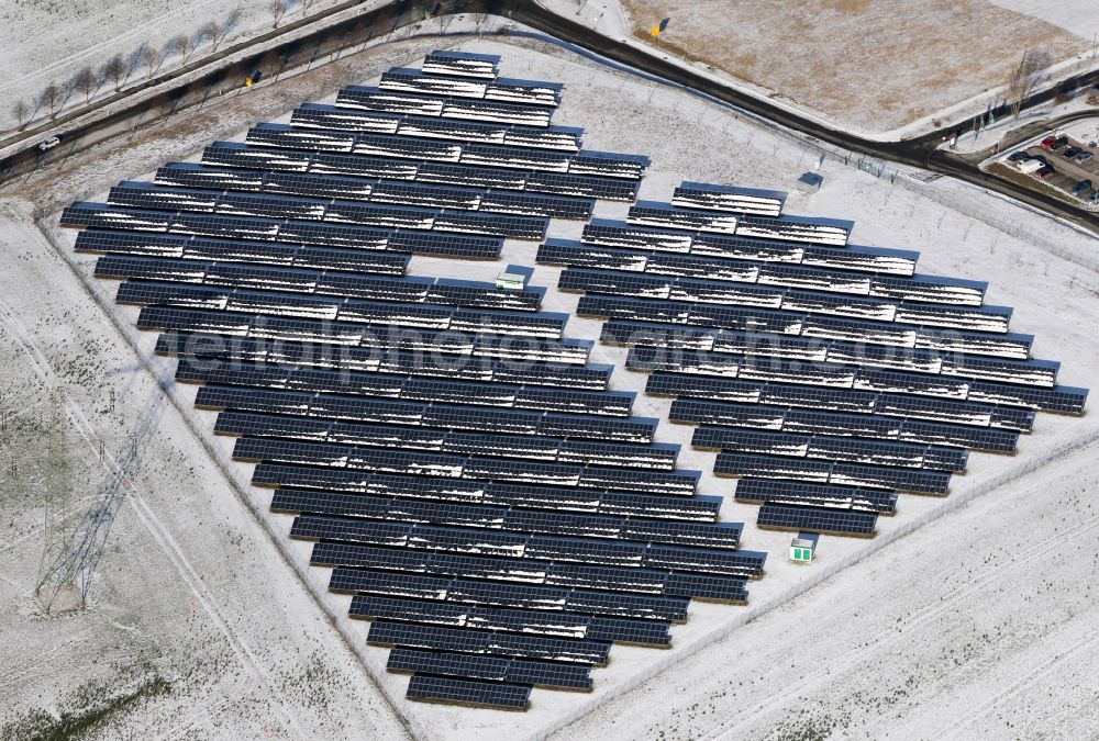 Aerial image Magdala - Wintry snowy panel rows of photovoltaic and solar farm or solar power plant in Magdala in the state Thuringia