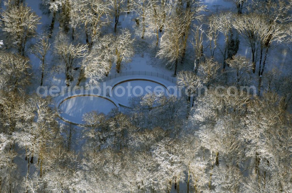 Aerial photograph Potsdam - Blick auf das winterlich vereiste und verscheite Achterbecken im Babelsberger Park. Nach jahrzehntelangen Verfall der Anlage am ehemaligen Grenzstreifen wurde der Wasserspeicher 2008 fertig restauriert und zum Betrieben der Fontaine auf dem Tiefen See nutzbar gemacht. Bereits im Mai 1845 konnte die erste Fontänenanlage am Babelsberger Park eingeweiht werden. Durch den Anbau einer neuen Maschinenhalle 1865, stand eine Dampfkraft von 65 PS für die Bewässerung des Parks zur Verfügung. Zu einem besonderen Schauspiel wurde die 40 Meter hohe Fontäne, die wie ein Geysir aus der Havel emporschoss. Nach dem Bau des Achterbecken erhielt die Parkanlage eine ausreichende Wasserversorgung.