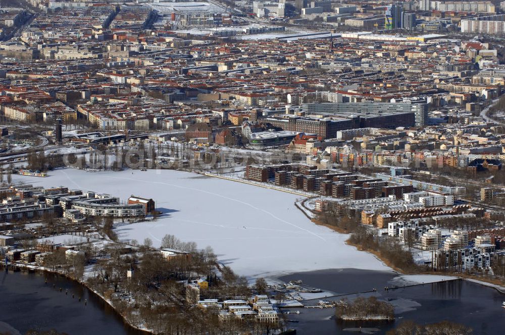 Berlin from the bird's eye view: Blick auf die winterlich verschneite Halbinsel Stralau mit den Wohnneubaugebieten an der Rummelsburger Bucht. Im Hintergrund die Baustelle zum Umbau des S- und Fernbahnhofes Berlin-Ostkreuz und die angrenzenden Wohngebiete.