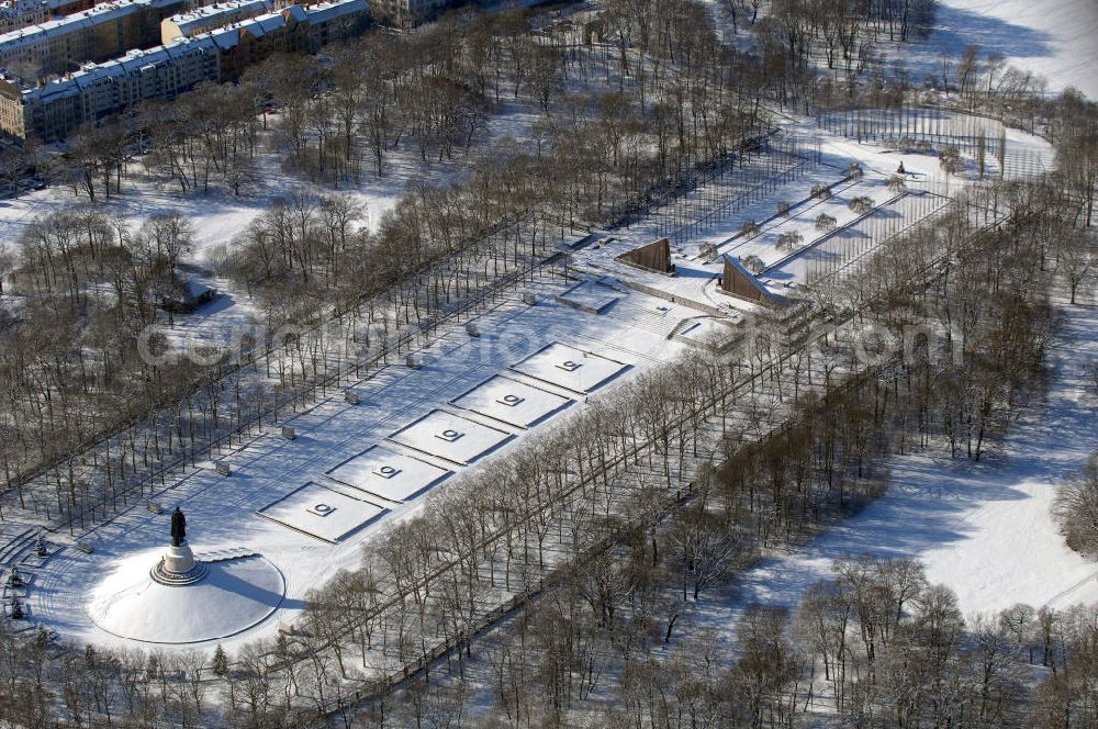 Aerial image Berlin - Blick auf das winterlich verschneite russische Ehrenmal in Berlin Treptow. Zur Gestaltung der Gedenkstätte wurde von den sowjetischen Besatzungstruppen ein Wettbewerb ausgelobt. Von Juni 1946 an wurde ein unter 52 eingereichten Entwürfen ausgewählter Vorschlag umgesetzt. Er stammt von einem sowjetischen „Schöpferkollektiv“, dem der Architekt Jakow S. Belopolski, der Bildhauer Jewgeni Wutschetitsch, der Maler Alexan der A. Gorpenko und die Ingenieurin Sarra S. Walerius vorstanden. Die Gedenkstätte wurde an Stelle der dort vorhandenen großen Spiel- und Sportwiese angelegt, im Mai 1949 wurde die Anlage vollendet.Im Oktober 2003 wurde die Statue des Rotarmisten in einer Werkstatt auf Rügen restauriert, mit einem Schiff wieder nach Berlin gebracht, und steht seit dem 4. Mai 2004 wieder auf ihrem Sockel.