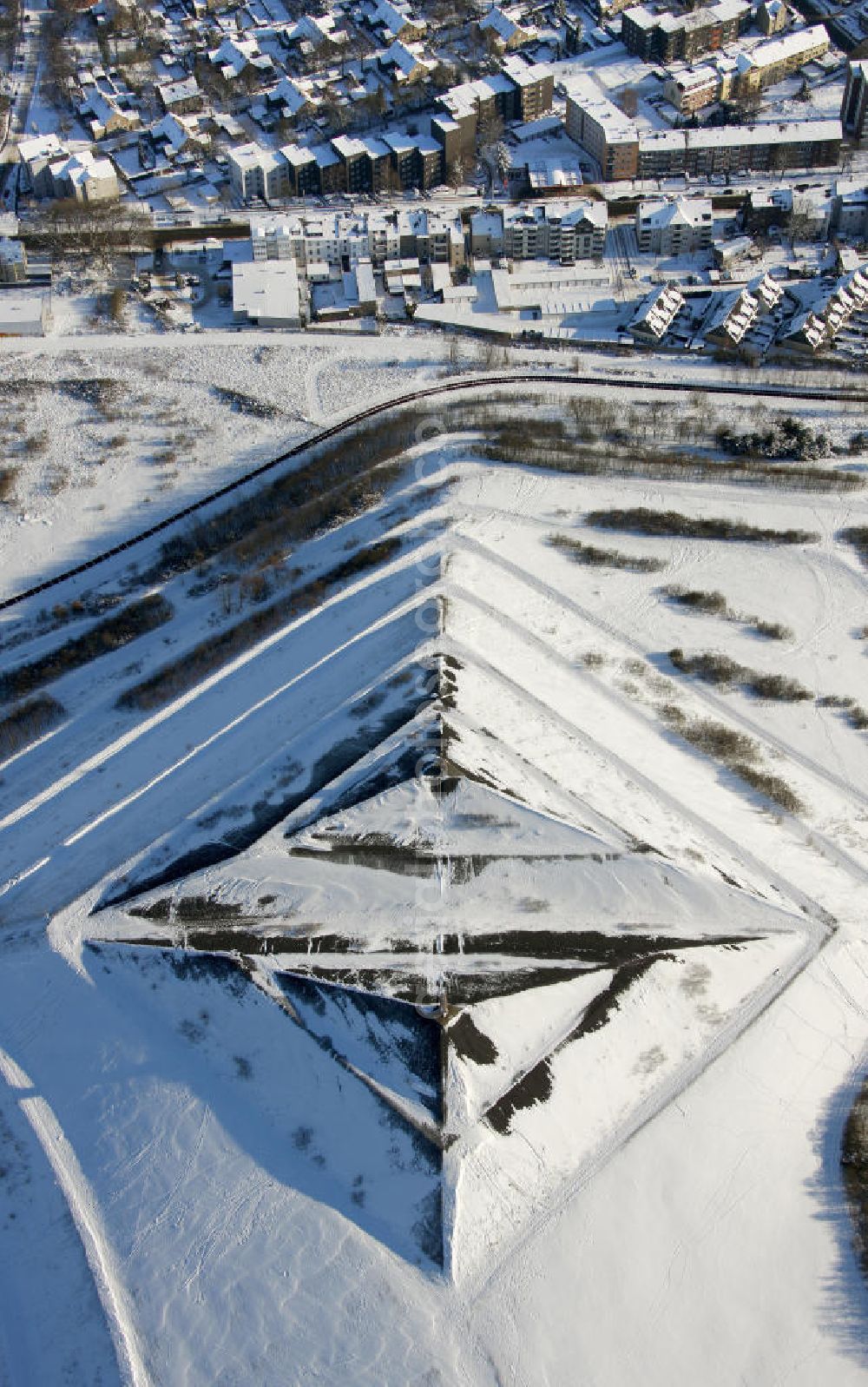 Gelsenkirchen - Buer from above - Blick auf die winterlich verschneite Schuttpyramide in Gelsenkirchen-Buer, Nordrhein-Westfalen. Die Schuttpyramide befindet sich in der Halde Rungenberg. Eine ungefähr 300 Stufen zählende Treppe, führt von der Siedlung Schüngelberg; hinauf zur in der Mitte geteilten Schuttpyramide. View of the snowy winter debris pyramid in Gelsenkirchen-Buer, Nordrhein-Westfalen. The pyramid is in the pile Rungenberg. About 300 steps counting staircase leads from the village Schüngelberg; up to the split in the middle of rubble pyramid.