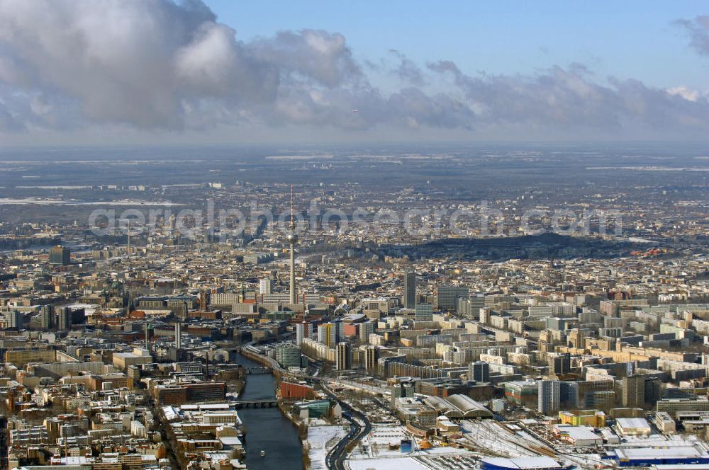 Berlin from the bird's eye view: Winterlich, verschneite Stadtansicht Berlins vom Bereich des Berliner Osthafens mit der dahinter liegenden O2 Arena im Friedrichshain und auf der kinken Spreeseite das Areal des Treptowers der ALLIANZ und Wohngebiete in Kreuzberg. Im Hintergrund das Berliner Stadtzentrum mit dem Berliner Fernsehturm