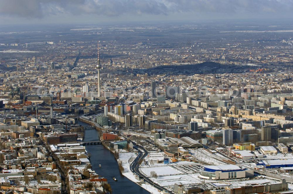 Aerial photograph Berlin - Winterlich, verschneite Stadtansicht Berlins vom Bereich des Berliner Osthafens mit der dahinter liegenden O2 Arena im Friedrichshain und auf der kinken Spreeseite das Areal des Treptowers der ALLIANZ und Wohngebiete in Kreuzberg. Im Hintergrund das Berliner Stadtzentrum mit dem Berliner Fernsehturm