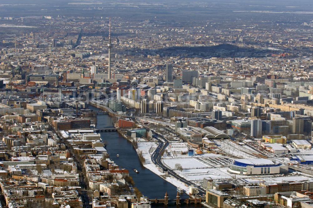 Berlin from the bird's eye view: Winterlich, verschneite Stadtansicht Berlins vom Bereich des Berliner Osthafens mit der dahinter liegenden O2 Arena im Friedrichshain und auf der kinken Spreeseite das Areal des Treptowers der ALLIANZ und Wohngebiete in Kreuzberg. Im Hintergrund das Berliner Stadtzentrum mit dem Berliner Fernsehturm