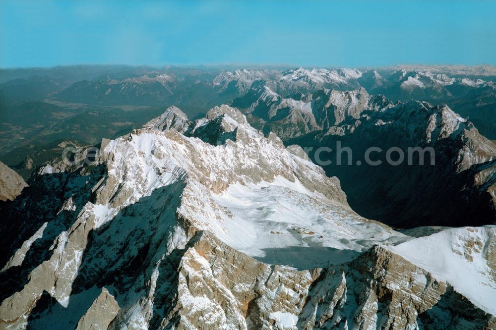 Garmisch-Partenkirchen from the bird's eye view: Blick auf die Zugspitze bei Garmisch-Partenkirchen, sie gehört zum Wettersteingebirge in den Nördlichen Kalkalpen und ist Grenzberg zwischen Deutschland und Österreich. Ihren Namen erhielt die Zugspitze durch die vielen Lawinenzüge (Lawinenstriche) am Nord-Fuß an ihren Steilhängen.Die Zugspitze ist der Hauptgipfel des Zugspitzmassivs, zu dem auch die übrigen, das Zugspitzplatt umrahmenden Gipfel (Schneefernerkopf, Wetterspitzen) bis hin zum Gatterl (2023 m) gezählt werden. Am Zugspitzmassiv treffen der Wetterstein-Hauptkamm (Grenze zwischen Österreich und Deutschland), der Blassenkamm und der Waxensteinkamm zusammen. Im Massiv befinden sich zwei der wenigen deutschen Gletscher, der Schneeferner und der Höllentalferner.