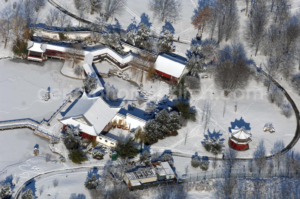 Berlin from the bird's eye view: Blick auf den winterlich verschneiten Chinesischen Garten im Erholungspark Marzahn. Der Erholungspark Marzahn liegt im Berliner Bezirk Marzahn-Hellersdorf am nördlichen Fuß des Kienbergs und wurde am 9. Mai 1987 anlässlich der 750-Jahr-Feier von Berlin als Berliner Gartenschau und Geschenk der Gärtner an die Hauptstadt der DDR (Ost-Berlin) eröffnet und sollte somit ein Gegenstück zum Britzer Garten im damaligen West-Berlin darstellen. 1991 wurde die Berliner Gartenschau nicht nur in Erholungspark Marzahn umbenannt, sondern auch umgebaut: Große Spiel- und Liegewiesen sowie neue Spielplätze entstanden, Bäume wurden gepflanzt und Sondergärten überarbeitet und erweitert. Der neu gestaltete Park sollte den 300.000 Bewohnern der umliegenden Großsiedlungen als vielfältig nutzbare Erholungslandschaft dienen. Seit Oktober 2000 ist diese durch ihre Gärten der Welt auch weit über die Stadtgrenzen hinaus bekannt. 2005 wurde der Chinesische Garten im Erholungspark Marzahn als drittschönste Parkanlage Deutschlands ausgezeichnet. Außerdem gehört der Erholungspark zu den 365 Orten im Land der Ideen.